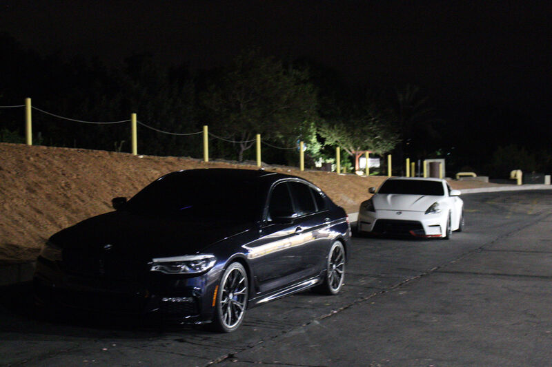 BMW 540i parked next to a Nissan 370Z - car meet vibes